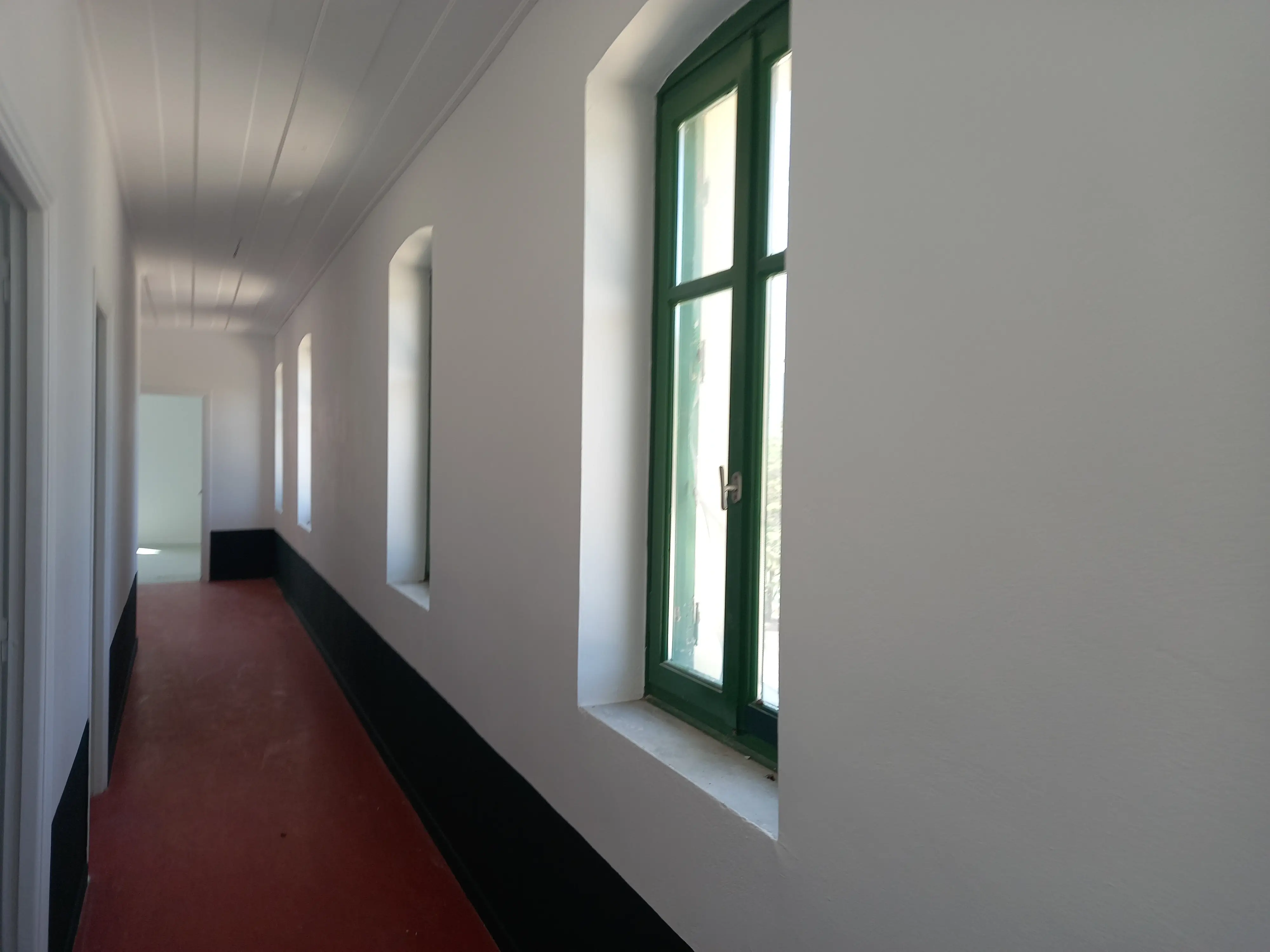 Απεικόνιση του εσωτερικού κτηρίου διοικήσεως. Απεικονίζεται το χολ και τα τέσσερα παράθυρα. Το πάτωμα έχει κόκκινο χρώμα, οι τοίχοι έχουν άσπρο χρώμα και τα παράθυρα έχουν πράσινο χρώμα.